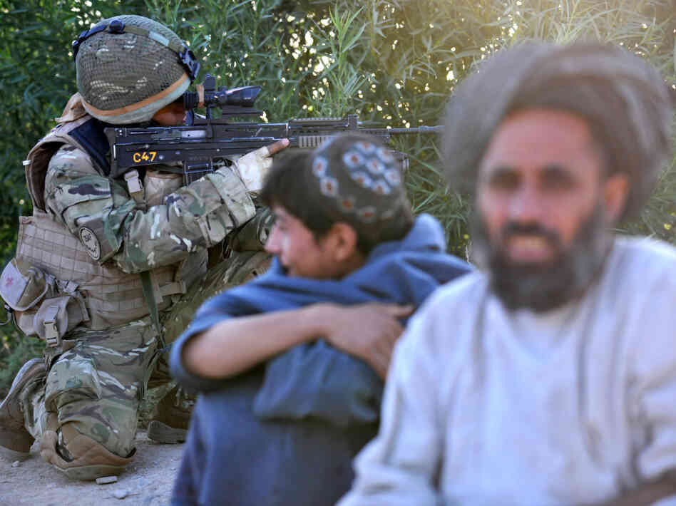Afghan residents look on as a soldier fr Afghan residents look on as a soldier fr
